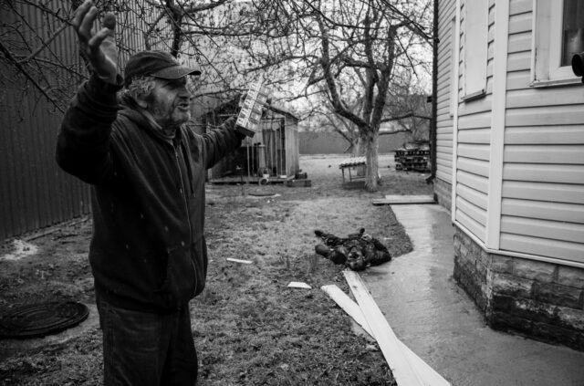 A devastated man near the body of a Russian soldier who was looting the house.