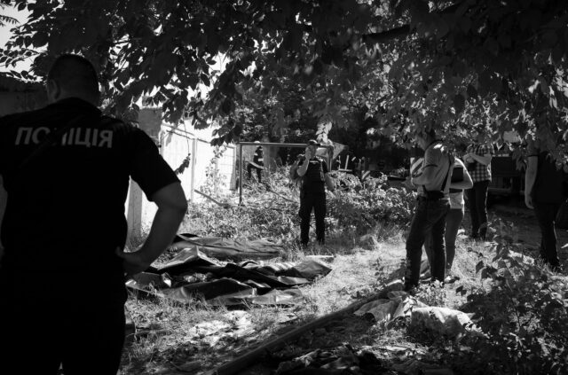 Emergency services near an apartment building in Mykolaiv after a Russian missile attack - near body bags, a man is calling on the phone.