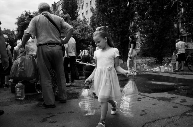 A girl in a dress fetches potable, drinking water.