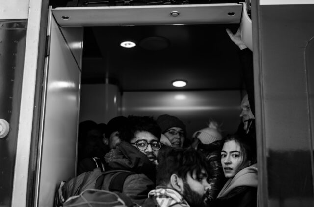 People looking scared in the dooropening of an overcrowded train leaving Kyiv.