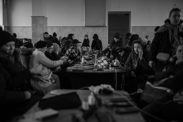 People use a free generator recharge phones, talk to their loved obnes, family and friends, send messages, it is a large hall filled with people at tables at Kherson train station.