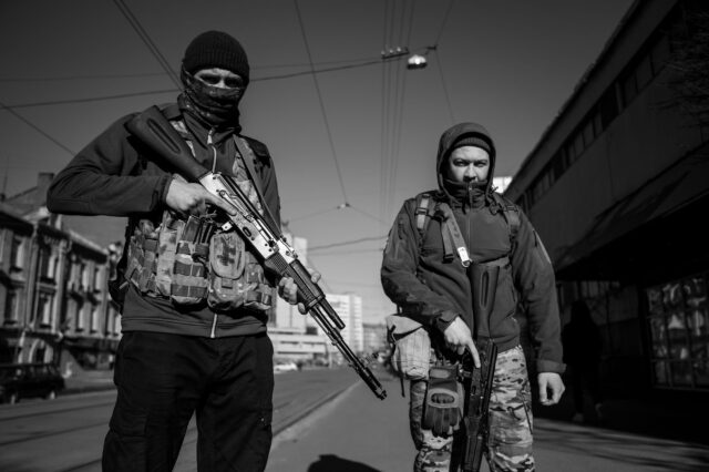 Armed forces in the streets of Kyiv with weapons ready, looking down.