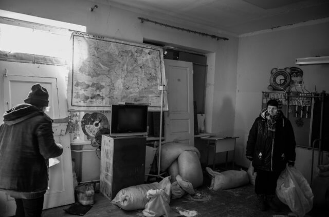 woman standing in a class room looking around. A classroom in a children's school, the Russian army used it as their operations base and as a human shield from Ukrainian defence forces.